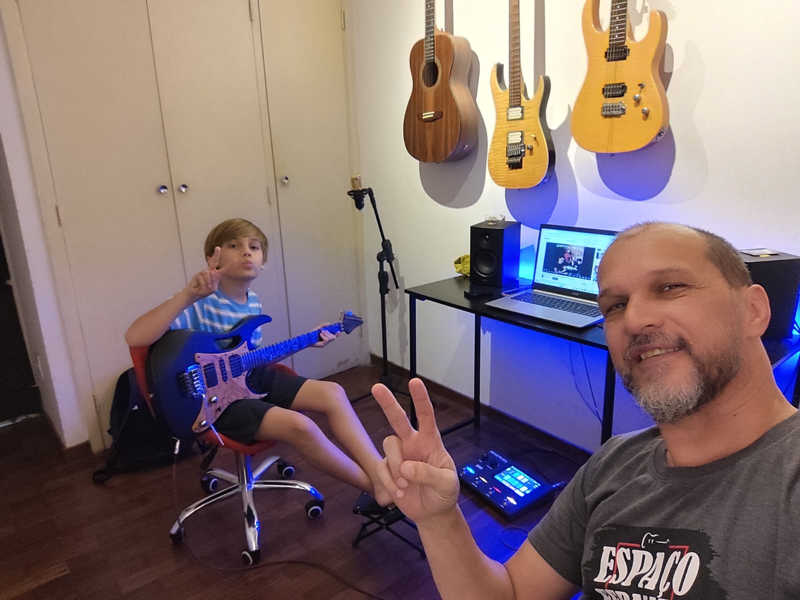 Criança e professor em sala tocando guitarra.